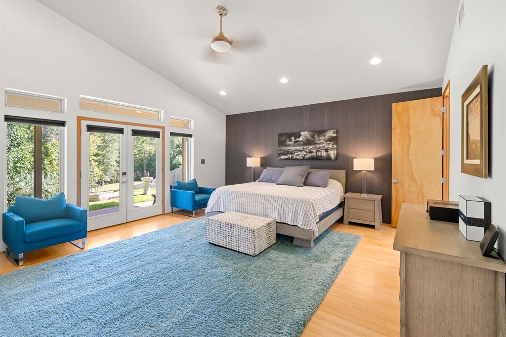 Vaulted ceilings featuring recessed lighting, a ceiling fan, wood-finish flooring, a full-height accent wall, and glass-paneled double doors with transom windows