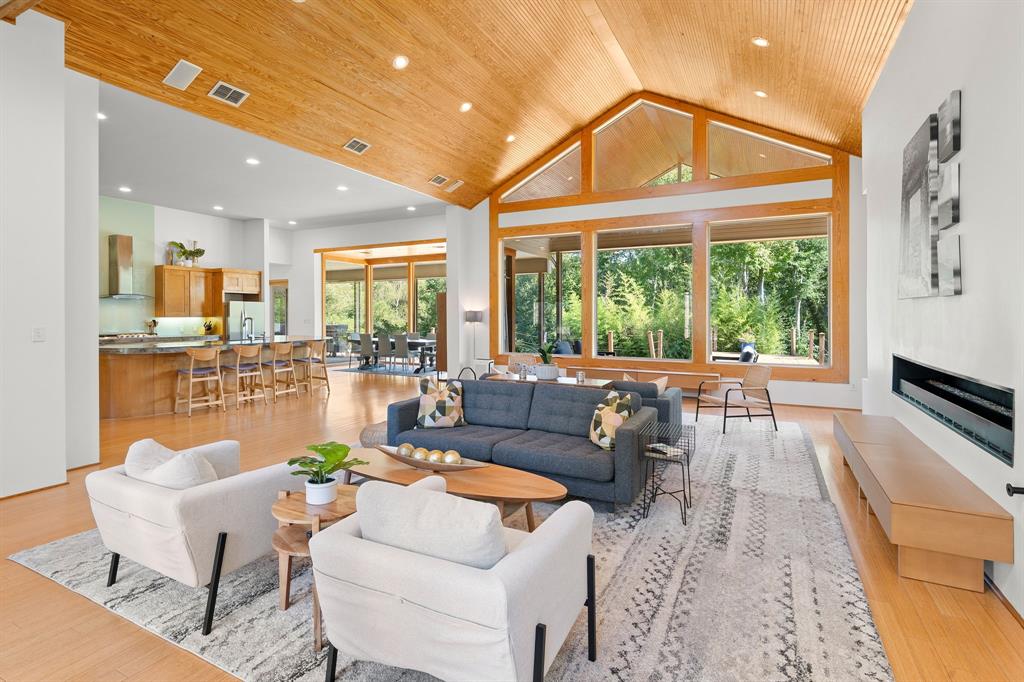 Vaulted wood-plank ceiling, floor-to-ceiling windows with wood casing, linear gas fireplace with built-in bench, recessed lighting, and wood-finish flooring
