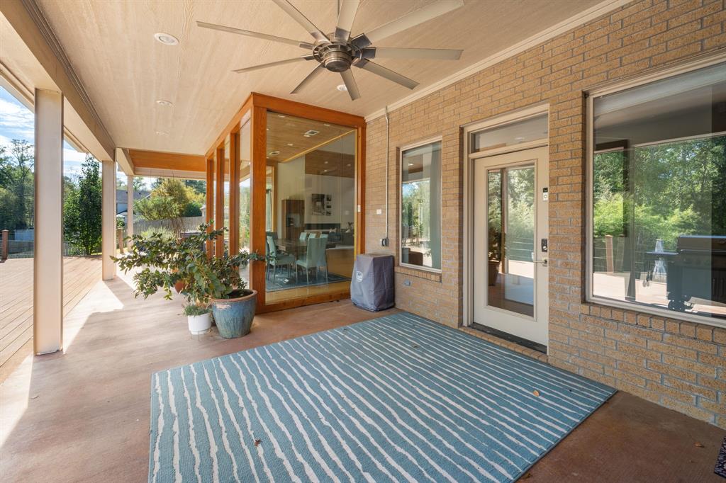 Covered patio featuring a brick exterior, tongue-and-groove ceiling, industrial-style ceiling fan, and large glass paneled door