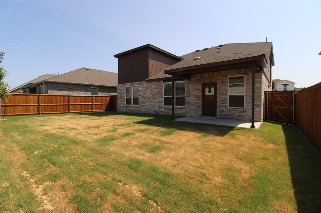 Rear exterior featuring a brick and horizontal siding facade, covered patio, and enclosed wood privacy fencing