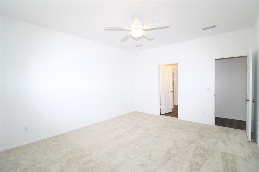 Room featuring neutral wall-to-wall carpeting, white walls, a ceiling fan with integrated light fixture, and two interior doors