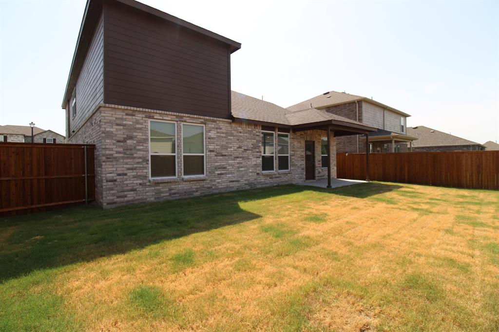 Exterior featuring mixed-material brick and horizontal siding, covered rear patio, and a fully fenced backyard