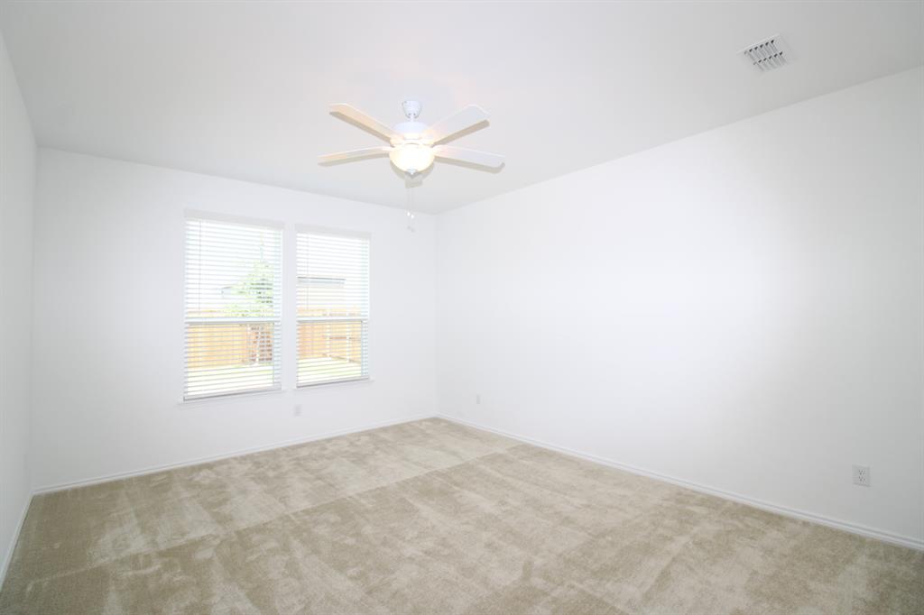 Neutral-toned wall-to-wall carpeting, dual windows with horizontal blinds, and a white ceiling fan with integrated lighting