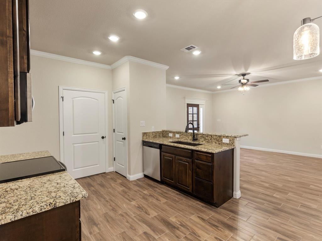 Kitchen featuring dark wood cabinetry, stone countertops, stainless steel dishwasher, wood-finish flooring, and recessed lighting Kitchen featuring dark wood cabinetry, stone countertops, stainless steel dishwasher, wood-finish flooring, and recessed lighting