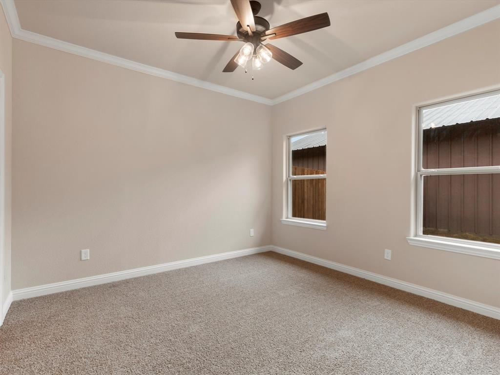 Neutral-toned interior featuring wall-to-wall carpeting, crown molding, double-hung windows, and a central ceiling fan with multi-light fixture Neutral-toned interior featuring wall-to-wall carpeting, crown molding, double-hung windows, and a central ceiling fan with multi-light fixture