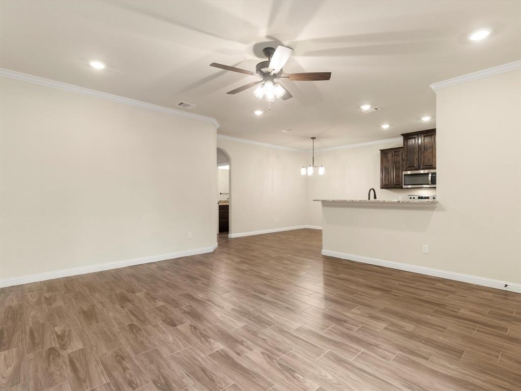 Interior featuring wood-finish tile flooring, recessed lighting, a multi-blade ceiling fan, crown molding, and an arched entryway Interior featuring wood-finish tile flooring, recessed lighting, a multi-blade ceiling fan, crown molding, and an arched entryway