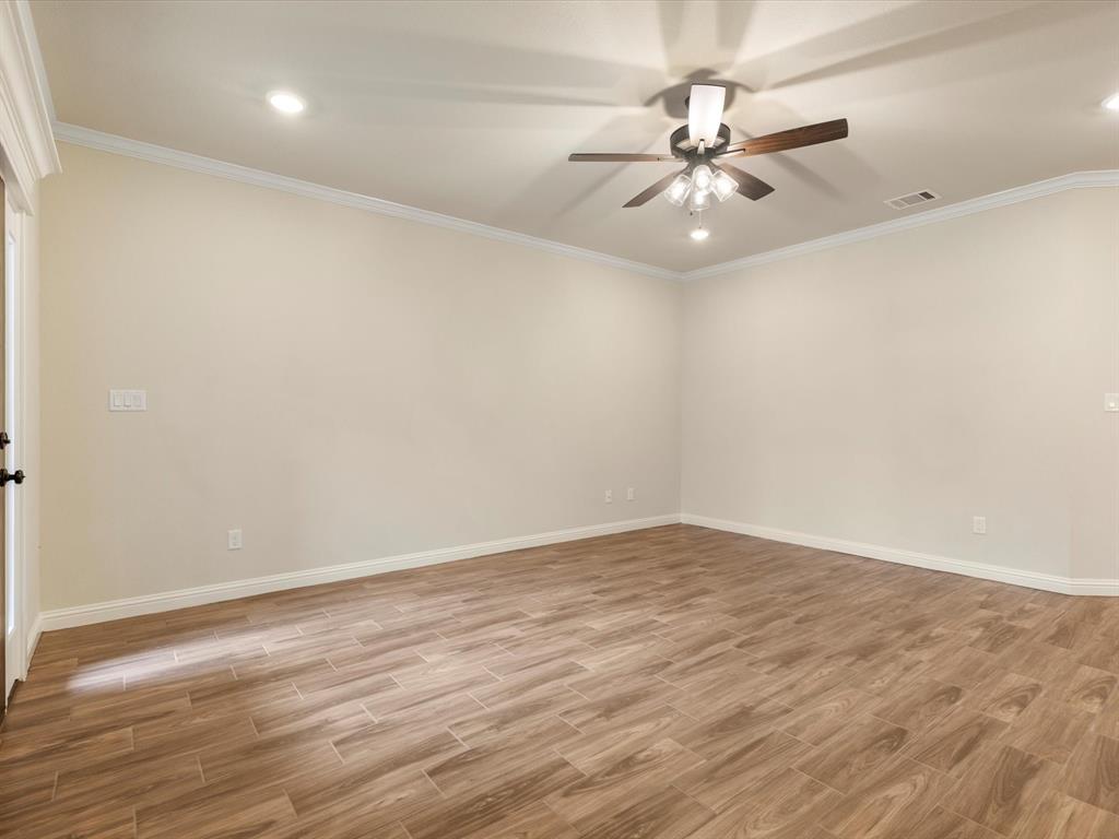 Room featuring wood-finish tile flooring, crown molding, recessed lighting, and a ceiling fan with integrated light fixture Room featuring wood-finish tile flooring, crown molding, recessed lighting, and a ceiling fan with integrated light fixture