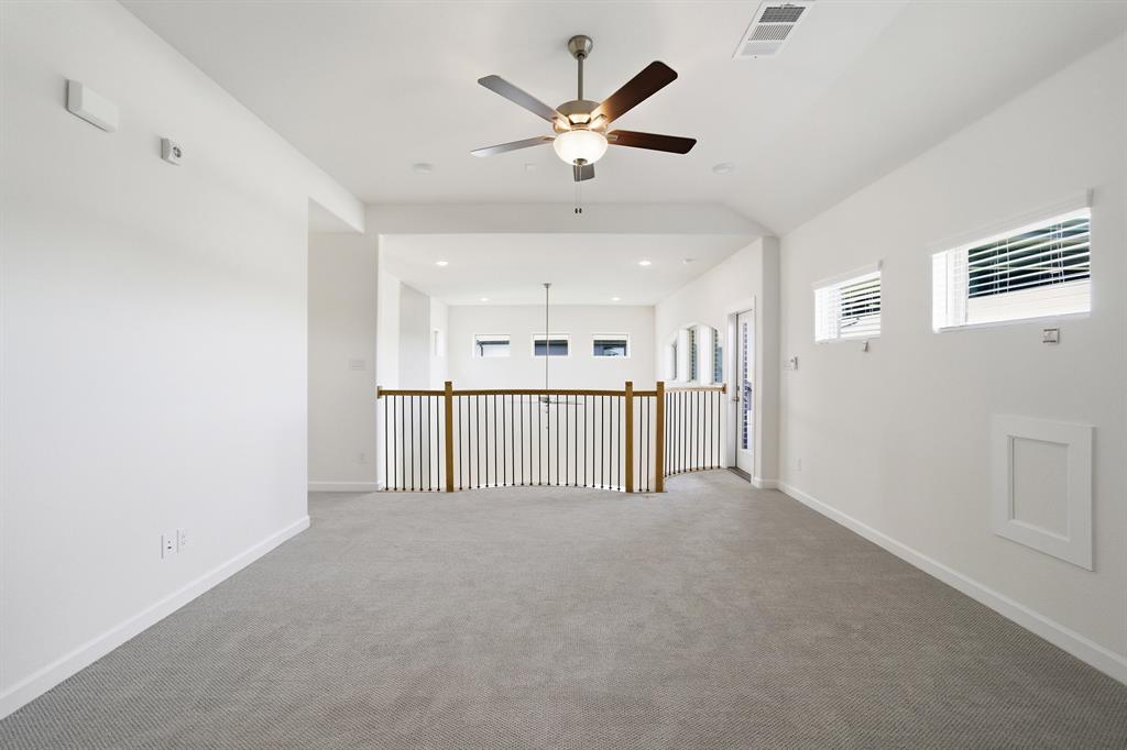 Carpeted loft area featuring a ceiling fan, multiple windows with blinds, and a white framed access panel