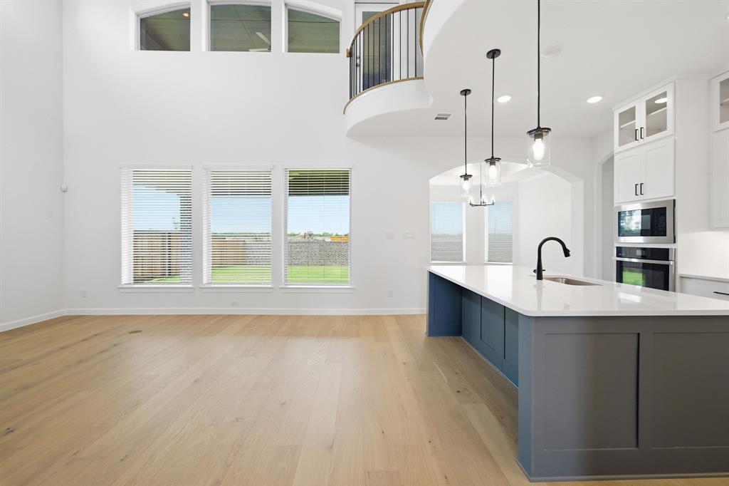 Open-concept living space featuring wood-finish flooring, a two-story ceiling, and a kitchen island with seating