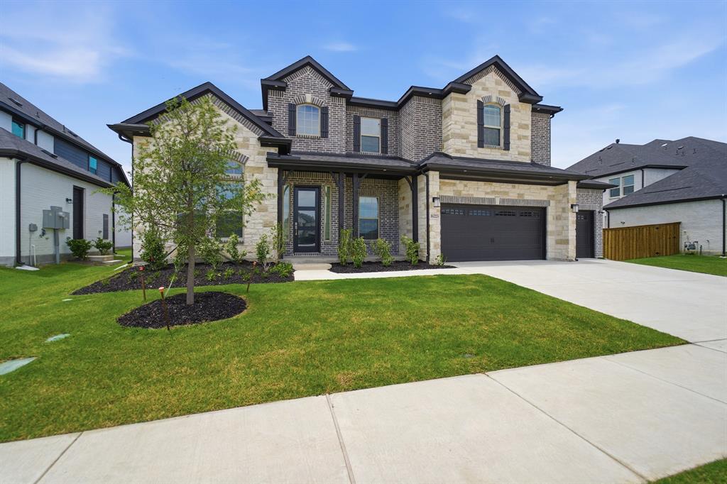 Two-story residence featuring a combination brick and stone facade with dark trim accents