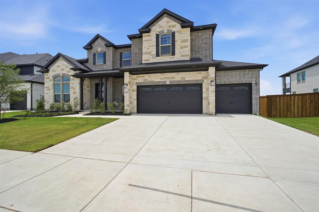 Stately two-story residence featuring a brick and stone facade, arched windows, and a covered entry