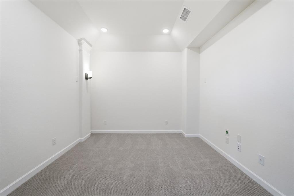Carpeted room featuring recessed ceiling lighting and a wall sconce
