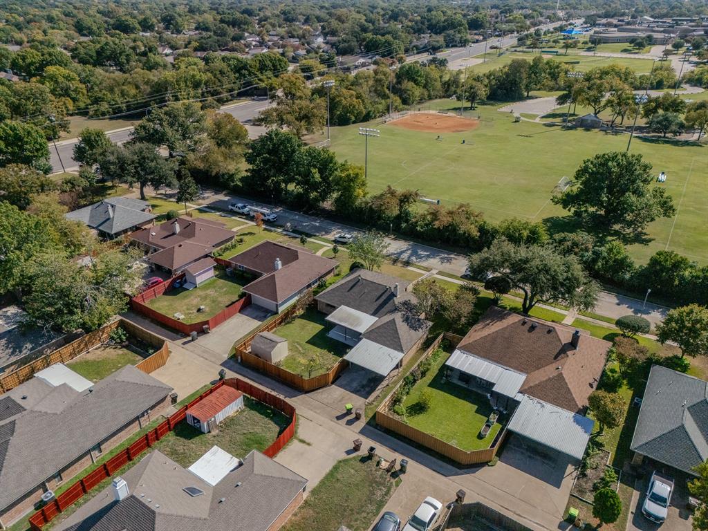 Aerial perspective featuring residential lots with fenced perimeters, paved driveways, and covered parking structures
