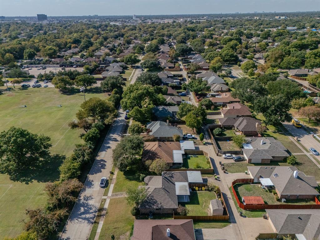 Aerial perspective of a residential neighborhood featuring established tree canopy, grass-covered open space, and suburban street grid