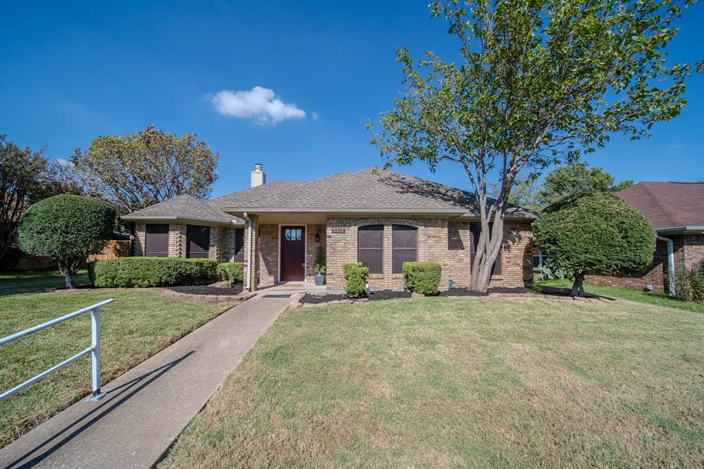 Single-story brick exterior featuring a hip roof, covered entryway, concrete walkway, and manicured landscaping
