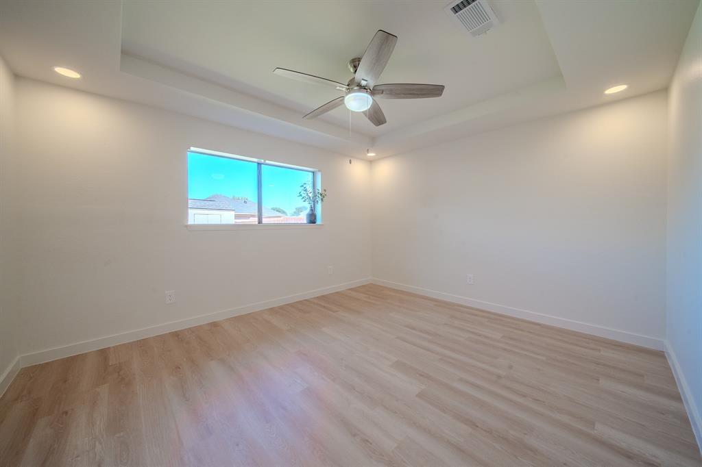 Tray ceiling featuring recessed lighting and a central ceiling fan, complemented by wood-finish flooring