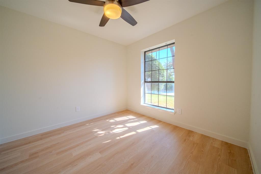 Room featuring wood-finish flooring, a multi-pane window, and a ceiling fan with integrated lighting