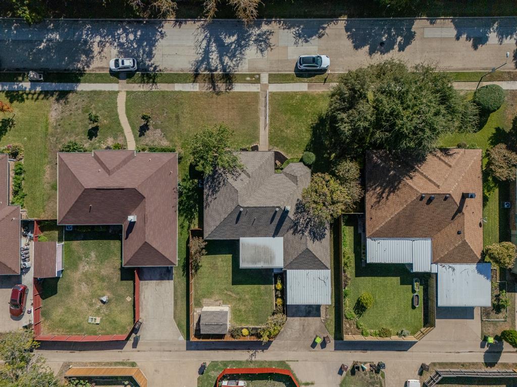 Aerial perspective featuring a residential property with a detached storage structure, concrete driveway, and a fenced backyard