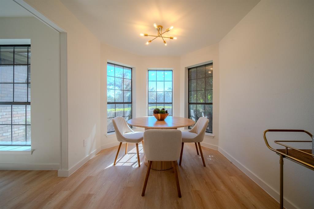Bay window area featuring multi-pane windows, wood-finish flooring, and a modern multi-arm brass light fixture