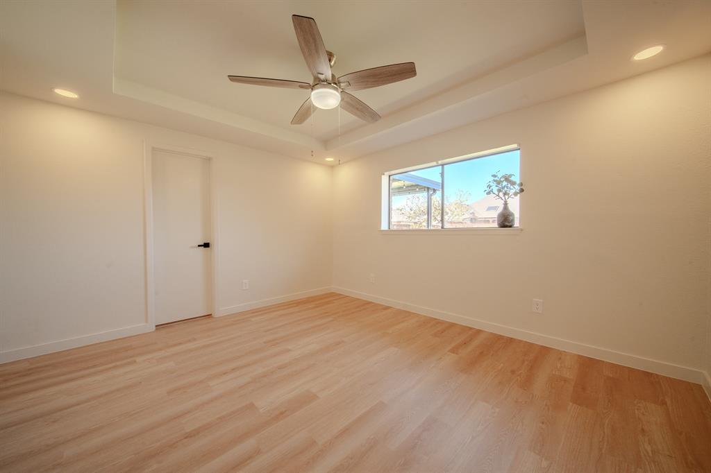 Tray ceiling room featuring wood-finish flooring, recessed lighting, and a multi-blade ceiling fan with integrated lighting