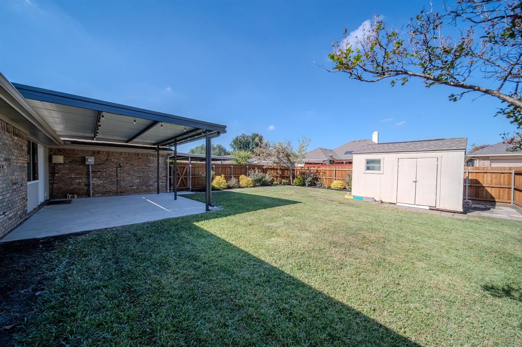 Backyard featuring a covered concrete patio, detached storage shed, privacy wood fencing, and open lawn space