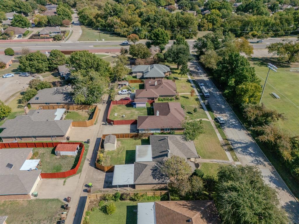 Aerial perspective of a residential neighborhood featuring established tree cover, concrete sidewalks, paved street infrastructure, and proximity to expansive open green space