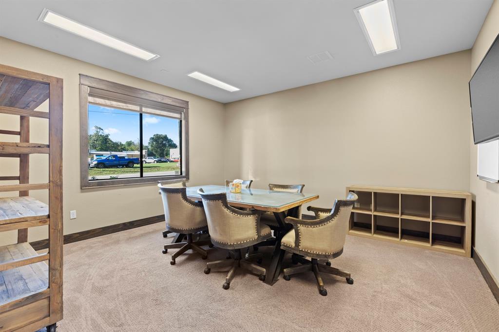 Multi-purpose room featuring recessed LED panel lighting, neutral carpeting, a large window with dark-finish trim, and built-in cubby shelving
