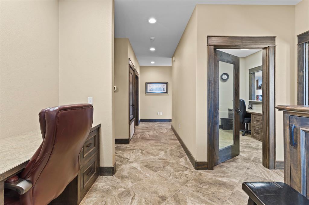 Hallway featuring stone-tile flooring, recessed lighting, and built-in desk cabinetry with a neutral countertop