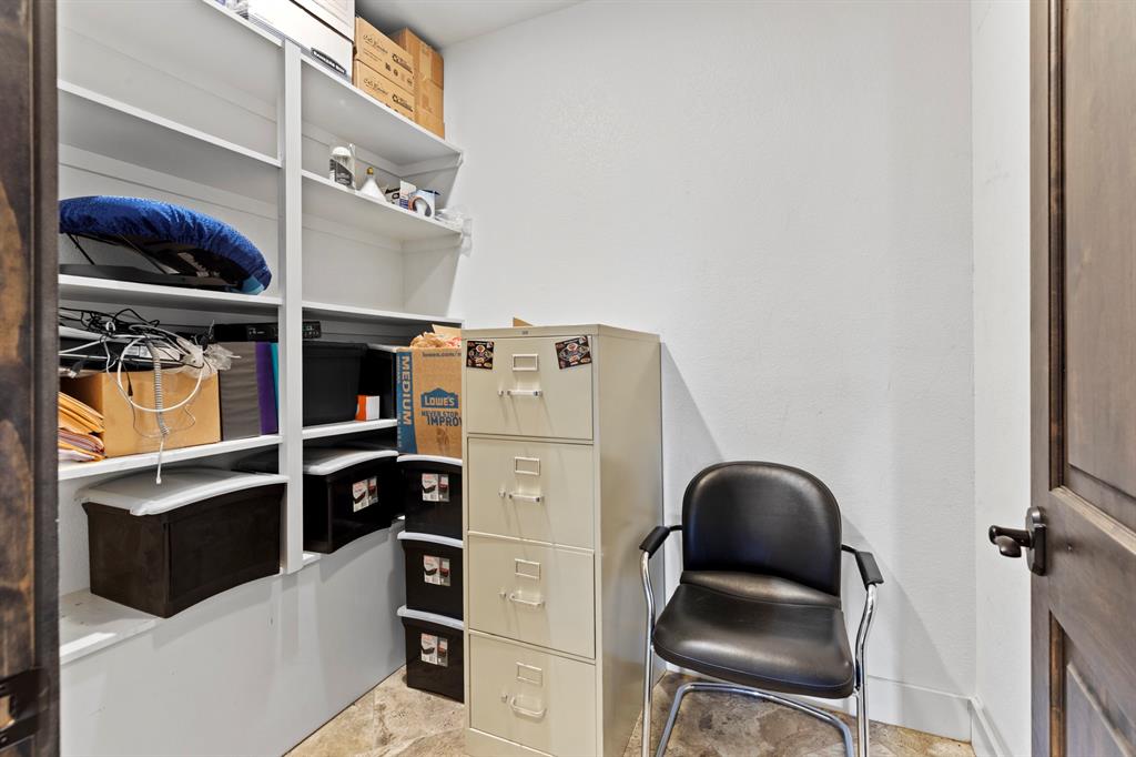 Storage space featuring white built-in shelving units and stained wood-finish door with black hardware