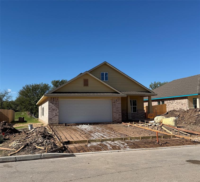 Exterior elevation featuring lap siding, brick masonry, a gabled roofline, and an attached two-car garage