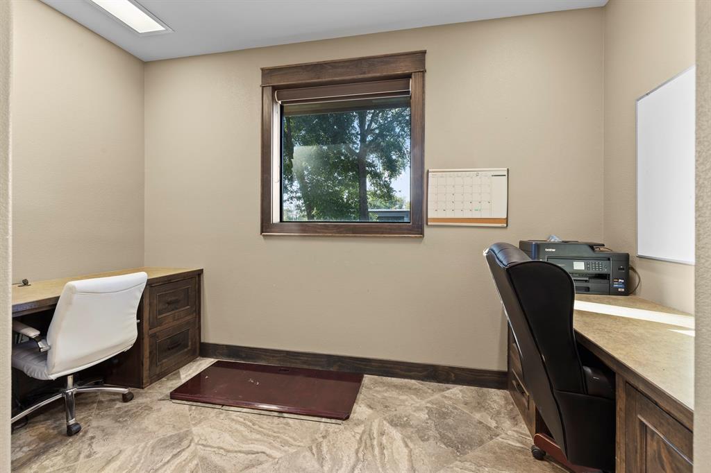 Custom wood-finish cabinetry with stone-surface countertops, recessed ceiling lighting, and tile flooring featuring natural stone-patterned veining