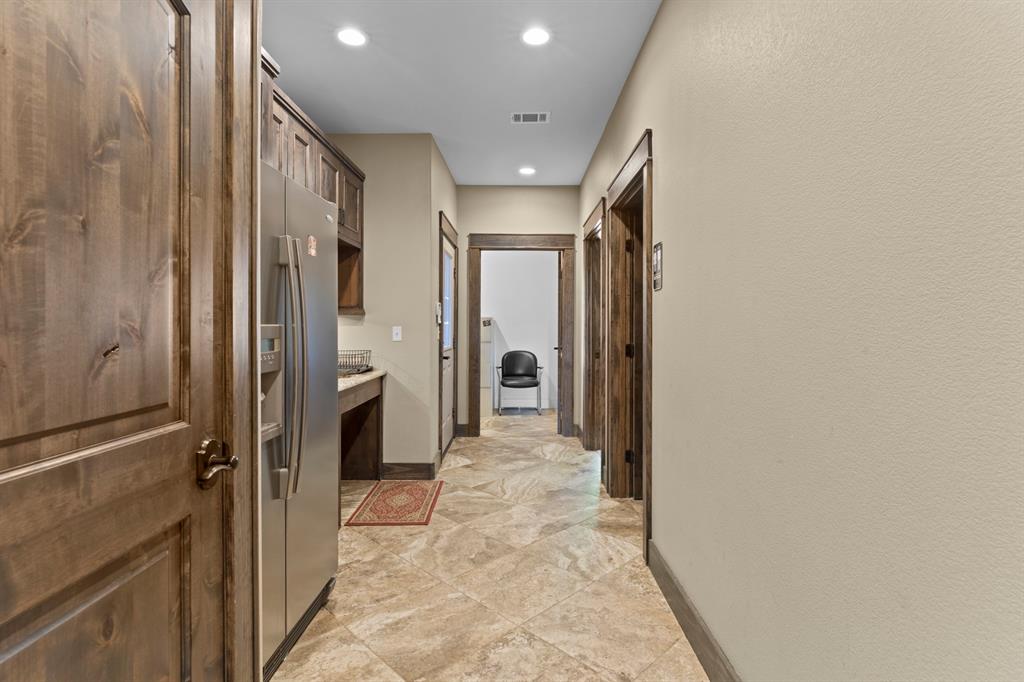 Stained wood door and door casings, stone-finish tile flooring, recessed ceiling lighting, and built-in cabinetry