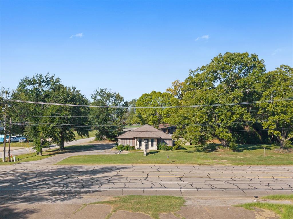 Single-story exterior featuring a hip roof, masonry facade, and mature landscaping on a spacious lot