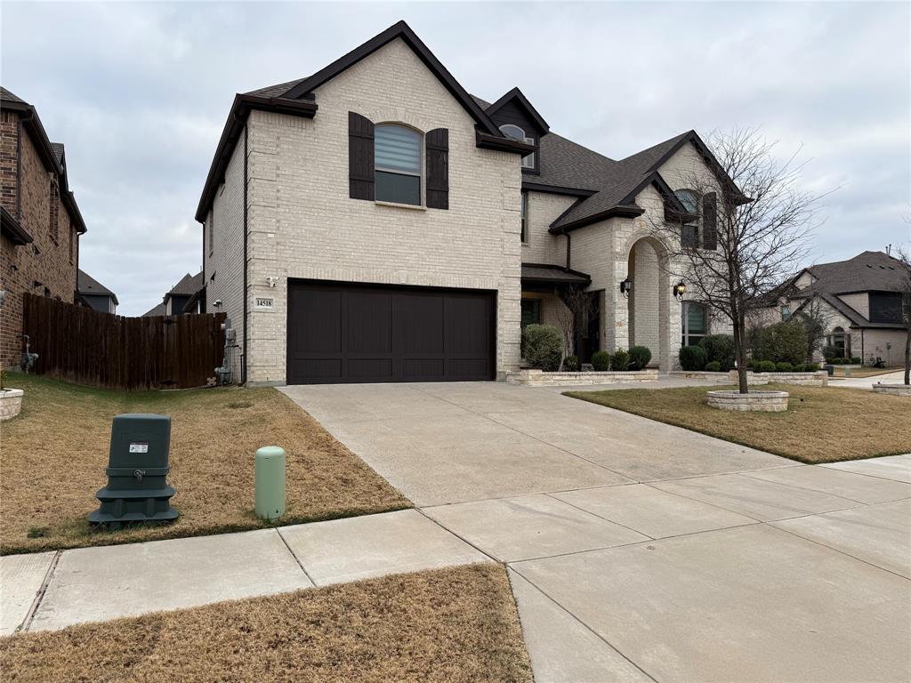 Two-story exterior featuring light-toned masonry, an arched stone-trimmed entryway, dark-finish shutters, and a multi-car garage