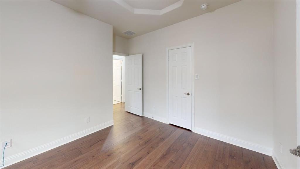 Interior room featuring wood-finish flooring, a tray ceiling, and dual interior doors