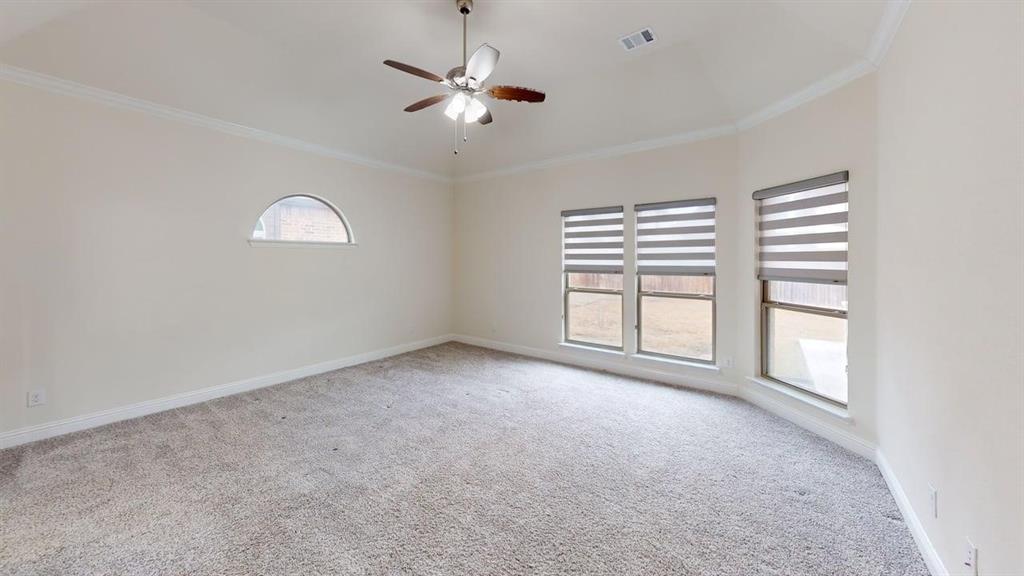 Vaulted ceiling featuring a central lighted ceiling fan, carpeted flooring, arched accent window, and triple-pane windows with integrated blinds