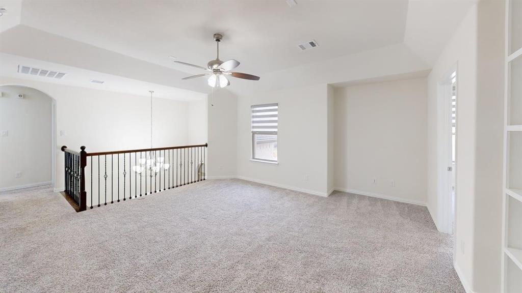 Vaulted ceiling, iron baluster railing, carpeted flooring, built-in shelving, and ceiling fan