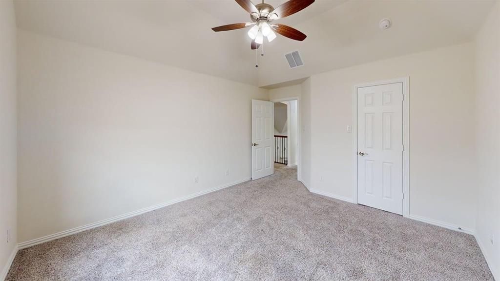 Neutral-toned room featuring a vaulted ceiling, carpeting, and a ceiling fan with integrated lighting