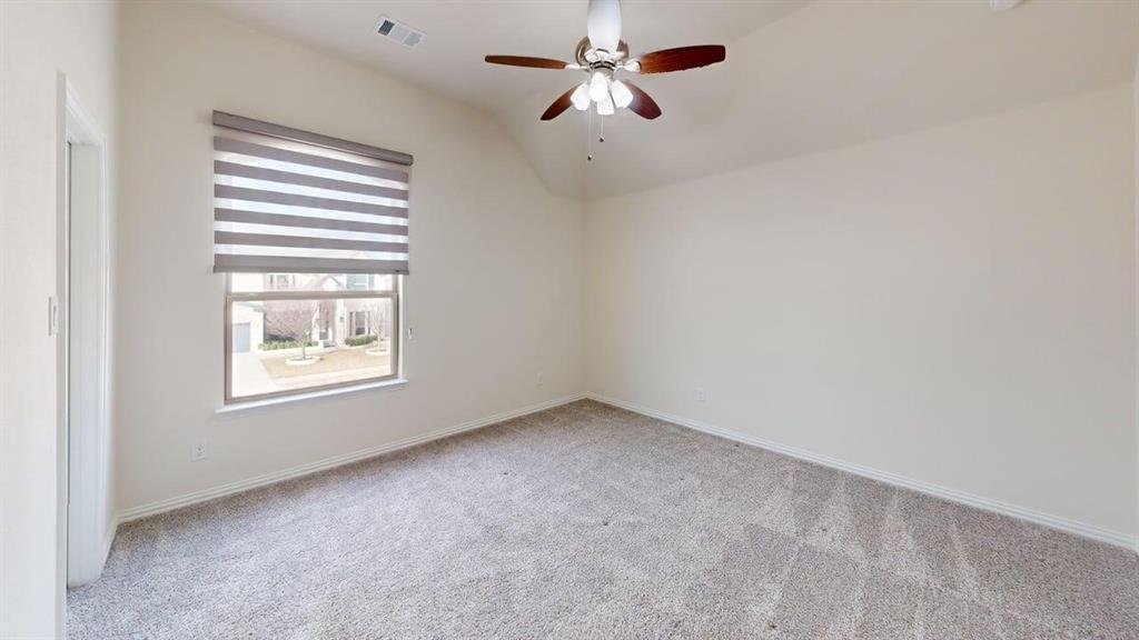Vaulted ceiling featuring a ceiling fan with integrated lighting, neutral carpeting, and a dual-shade window treatment