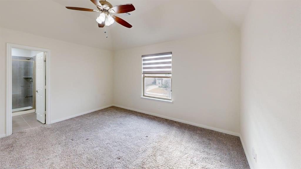 Room featuring a vaulted ceiling, ceiling fan with light fixture, neutral carpeted flooring, and a window with roller shade