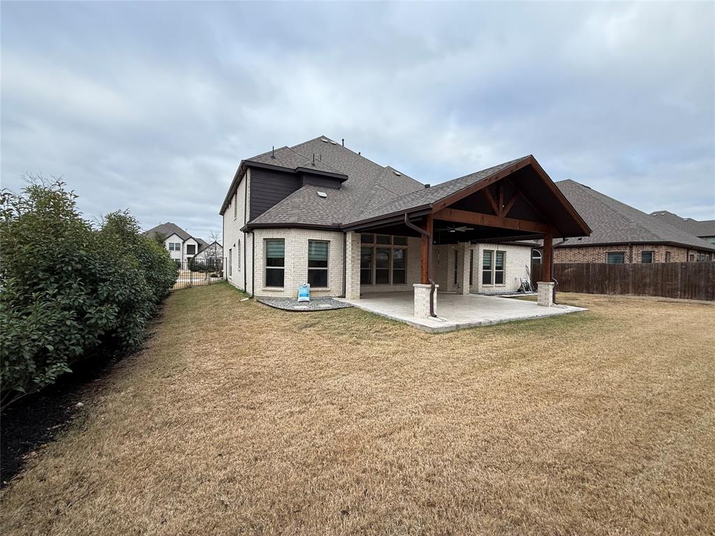 Brick exterior with a stone-accented covered patio, timber-framed roof structure, and perimeter fencing