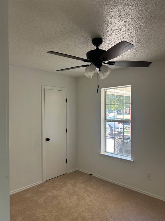 Neutral interior featuring wall-to-wall carpeting, a multi-blade ceiling fan with integrated lighting, and a single-hung window with a grille pattern