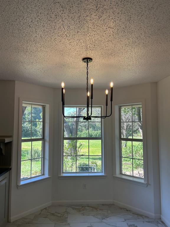 Bay window featuring multi-pane glass, matte black six-light chandelier, and stone-finish flooring