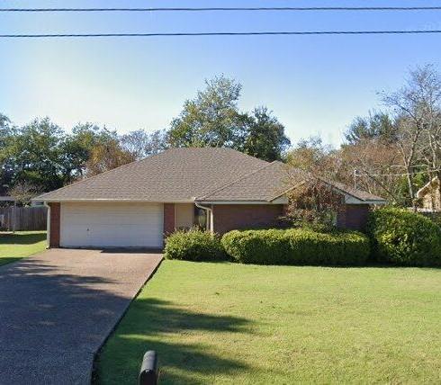 Single-story residence featuring a brick exterior, attached two-car garage, concrete driveway, and a front lawn with established landscaping