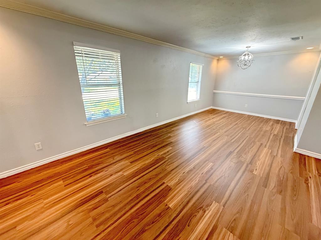 Wood-finish flooring, crown molding, chair rail, and a decorative orb chandelier