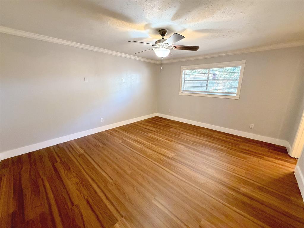 Room featuring wood-finish flooring, crown molding, and a central ceiling fan with integrated lighting