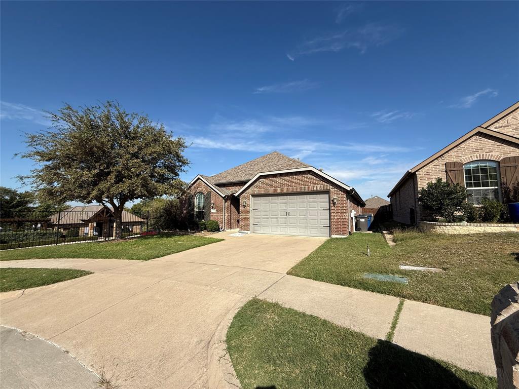 Brick exterior residence featuring a front-facing attached two-car garage, arched window accents, and a concrete driveway Brick exterior residence featuring a front-facing attached two-car garage, arched window accents, and a concrete driveway