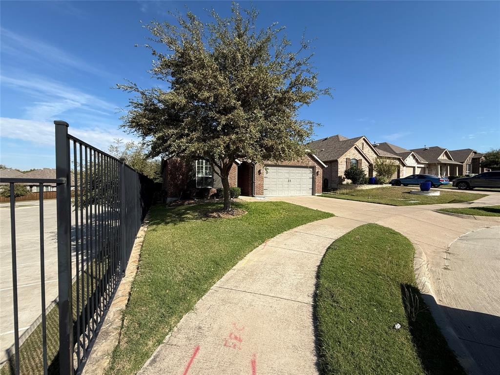 Brick exterior with attached two-car garage, metal picket fencing, and mature landscaping Brick exterior with attached two-car garage, metal picket fencing, and mature landscaping