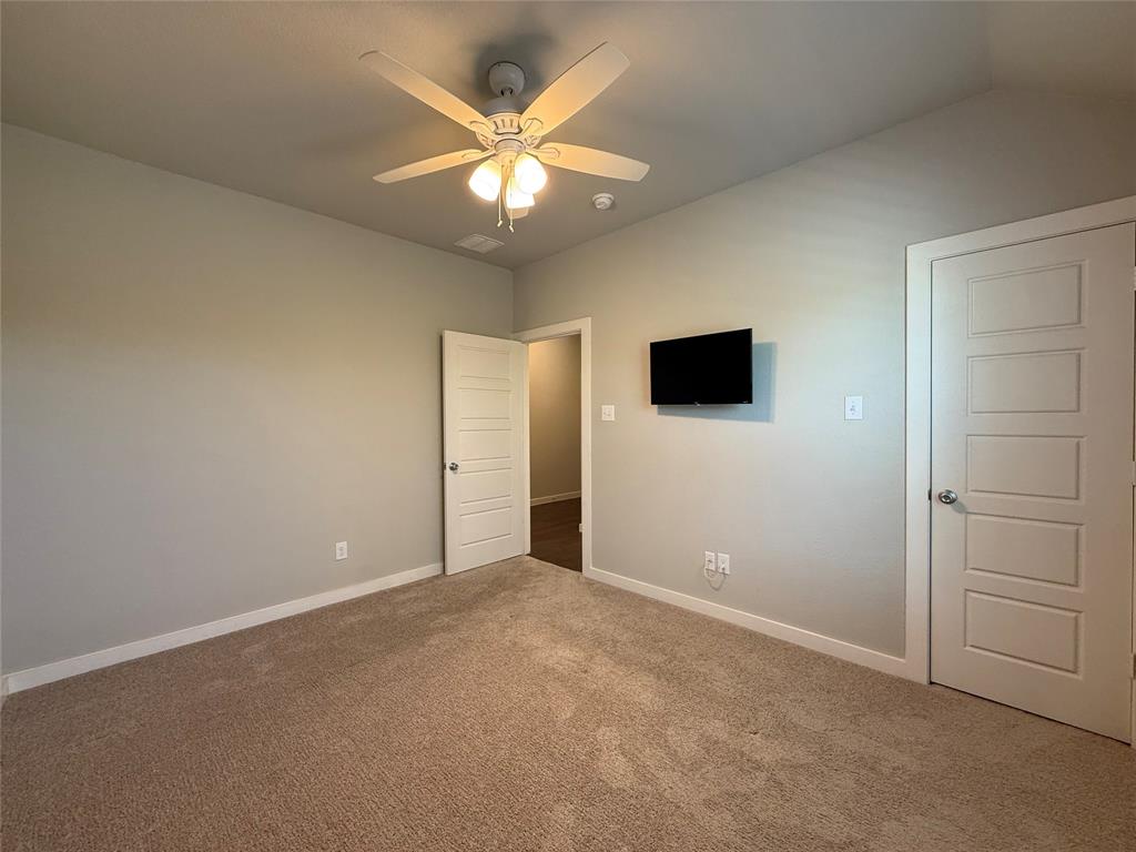 High ceilings, neutral wall tones, plush wall-to-wall carpeting, four-panel interior doors, and a central ceiling fan with integrated lighting