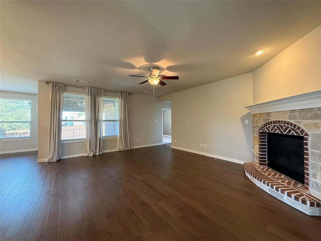 Open living space featuring wood-finish flooring, recessed lighting, ceiling fan, and a fireplace with brick masonry and stone detailing